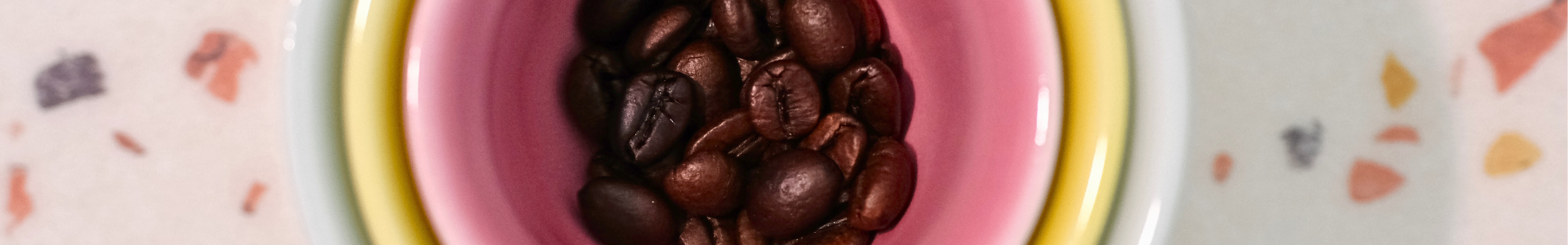 Ineinander gestapelte bunte Kaffeetassen mit Kaffeebohnen-Inhalt