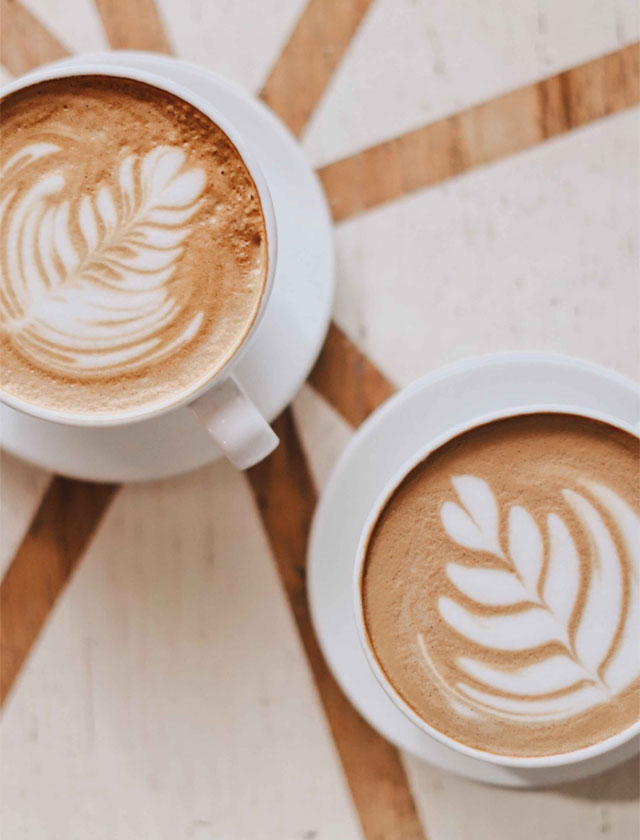 zwei weiße Tassen Cappuccino Latte-Art-Blatt