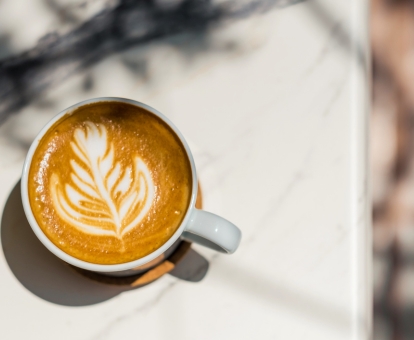 Latte Art Cappuccino steht auf einer hellen Mamorplatte