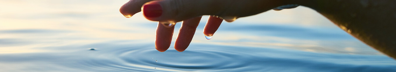 Schimmerndes Wasser mit einer Hand an der Wasseroberfläche