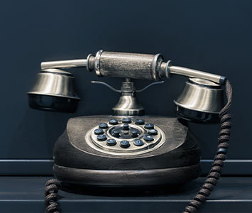 Schwarzes Telefon mit Drehscheibe vor blauer Wand