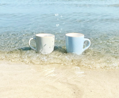 zwei Kaffeebecher stehen am Strand