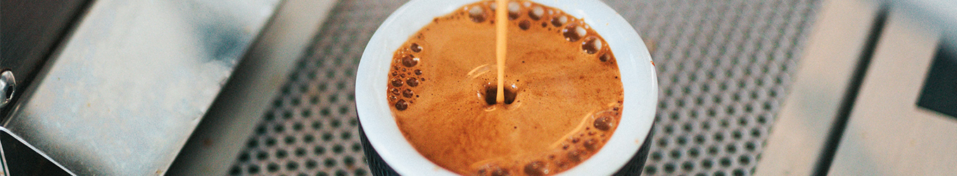 Espresso läuft in Tasse mit haselnussbrauner Crema