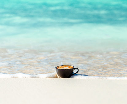 Latte-Art-Schwan Cappuccino in schwarze Keramiktasse am Strand