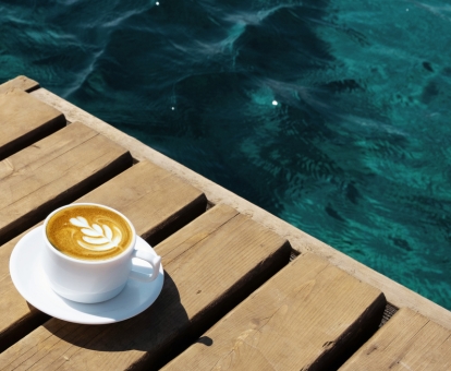 Kaffee steht auf einem Holzsteg im türkisen Wasser