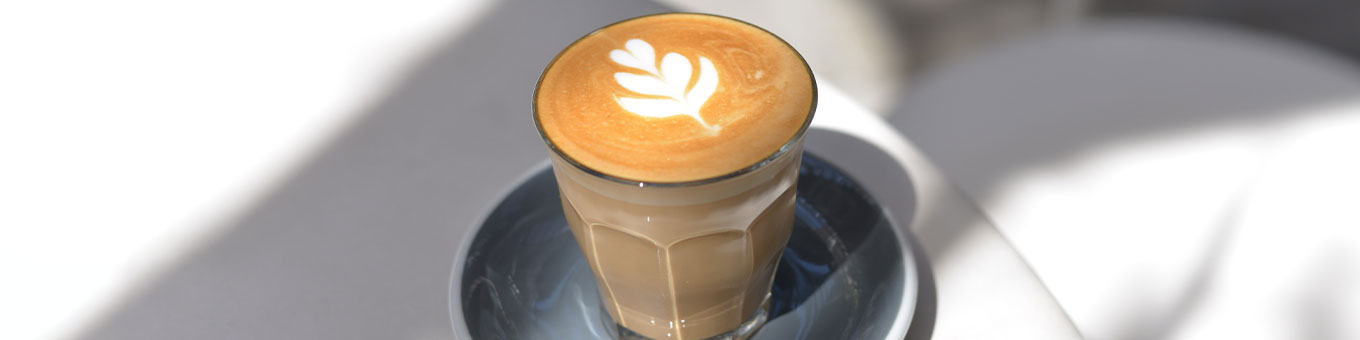 Cappuccino mit Latte-Art-Blatt in Glastasse