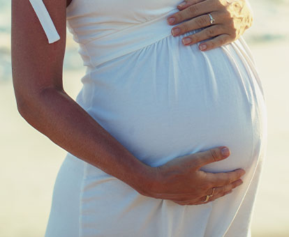 schwangere Frau formt mit ihren Händen ein Herz auf ihrem Bauch