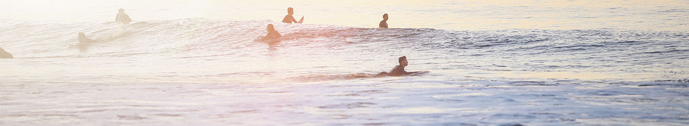 Personen surfen im Meer bei Sonnenaufgang